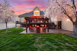 Back of house at dusk featuring a patio area, a pergola, and stucco siding