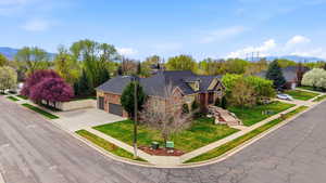 View of front of property with stone siding, a mountain view, concrete driveway, an attached garage, and a front lawn