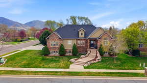 Traditional-style house featuring stone siding, stucco siding, a front yard, and a mountain view