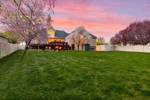 Back of house at dusk with a fenced backyard and a wooden deck