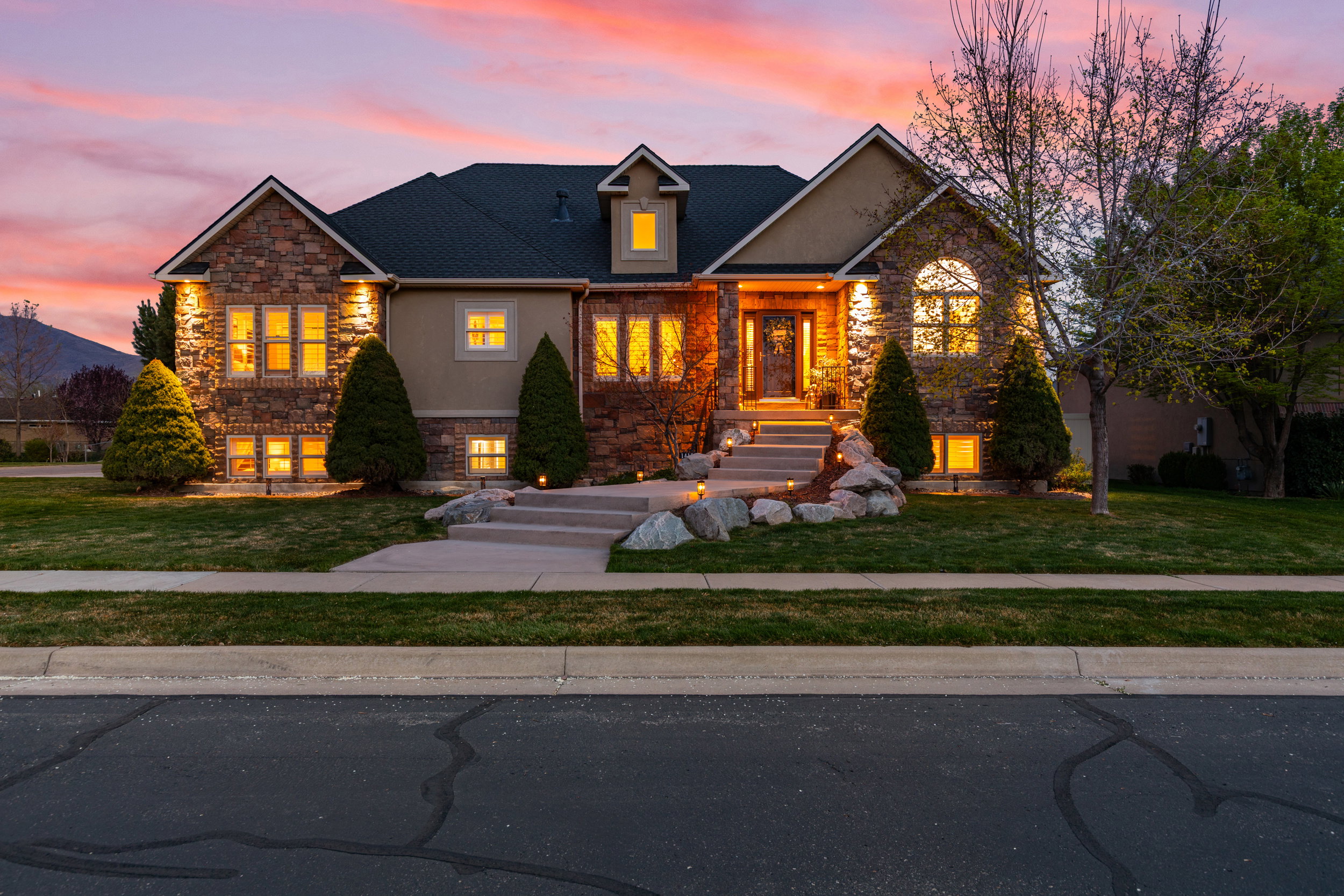 View of front of house featuring stone siding, a yard, and roof with shingles