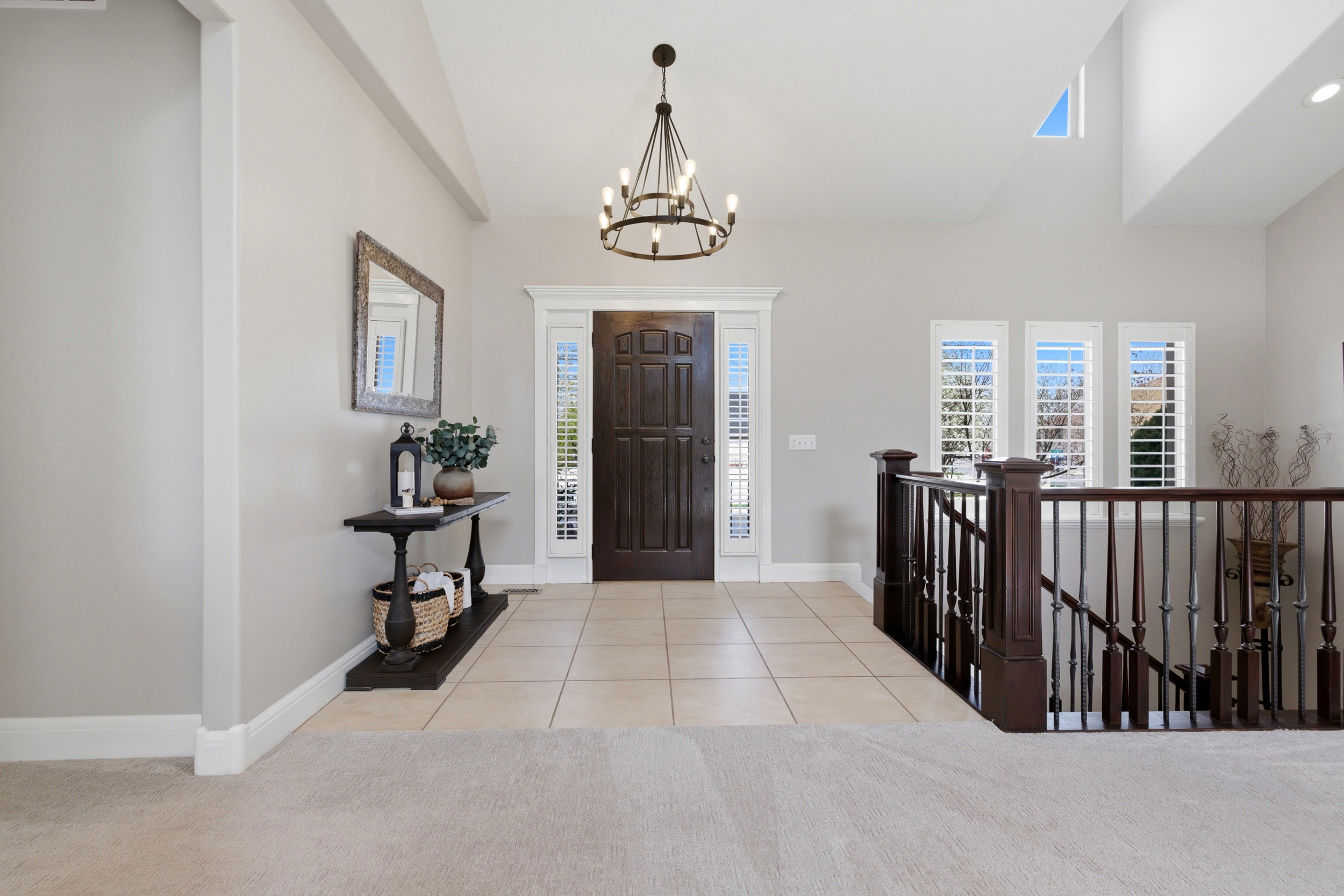 Entryway featuring a chandelier, light tile patterned floors, light carpet, and lofted ceiling