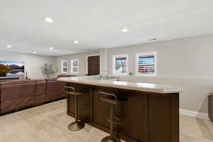 Kitchen featuring light countertops, open floor plan, dark wood finish cabinetry, recessed lighting, and a center island