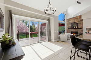 Unstaged Dining space with a stone fireplace, a chandelier, light tile patterned floors, and vaulted ceiling