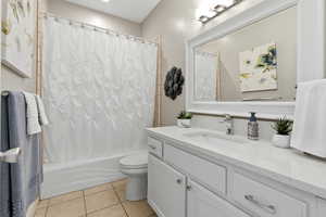 Bathroom featuring vanity, shower / bathtub combination with curtain, and light tile patterned floors