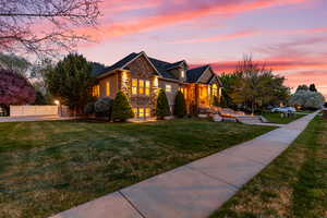 View of front of home with stone siding and a yard