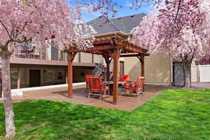 View of grassy yard featuring a pergola and a patio area