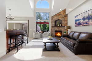 Living room featuring a high ceiling, a fireplace, light colored carpet, suspended lighting, and light tile patterned floors
