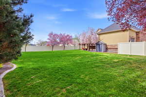 Fenced backyard with a storage unit, a pergola, and a patio area