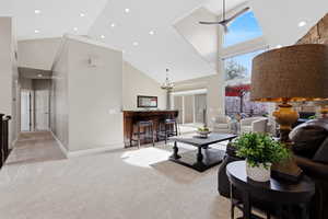 Living room with a high ceiling, light carpet, recessed lighting, and a ceiling fan