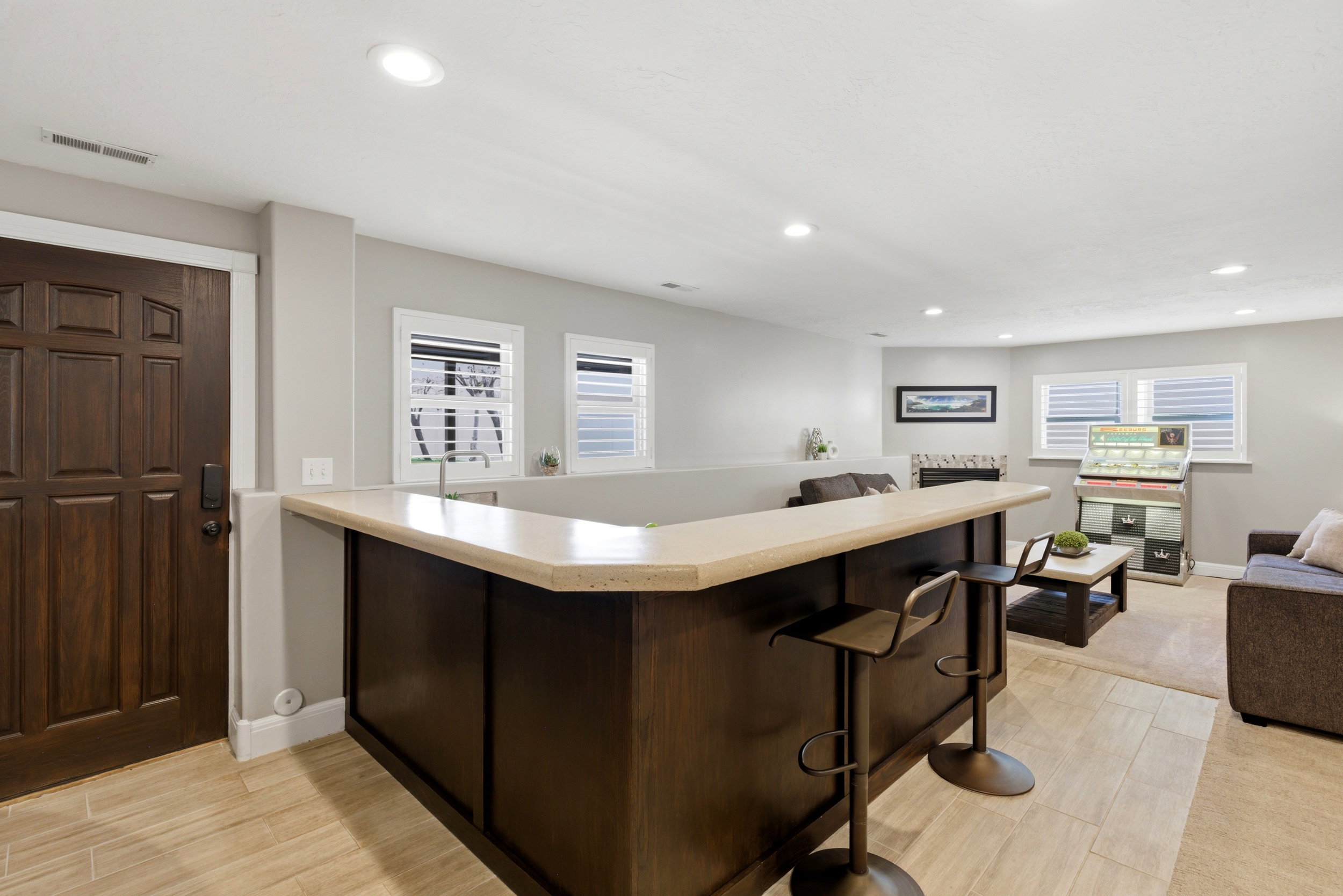 Bar with light countertops, wood finish floors, dark wood finish cabinets, and recessed lighting