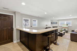 Bar with light countertops, wood finish floors, dark wood finish cabinets, and recessed lighting