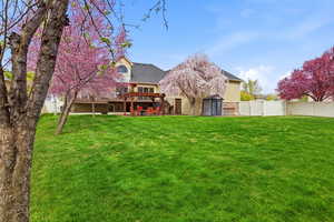 Rear view of property featuring a storage unit, a fenced backyard, a patio, roof with shingles, and a wooden deck