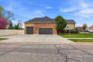 View of front of property featuring stucco siding, an attached garage, concrete driveway, roof with shingles, and stone siding