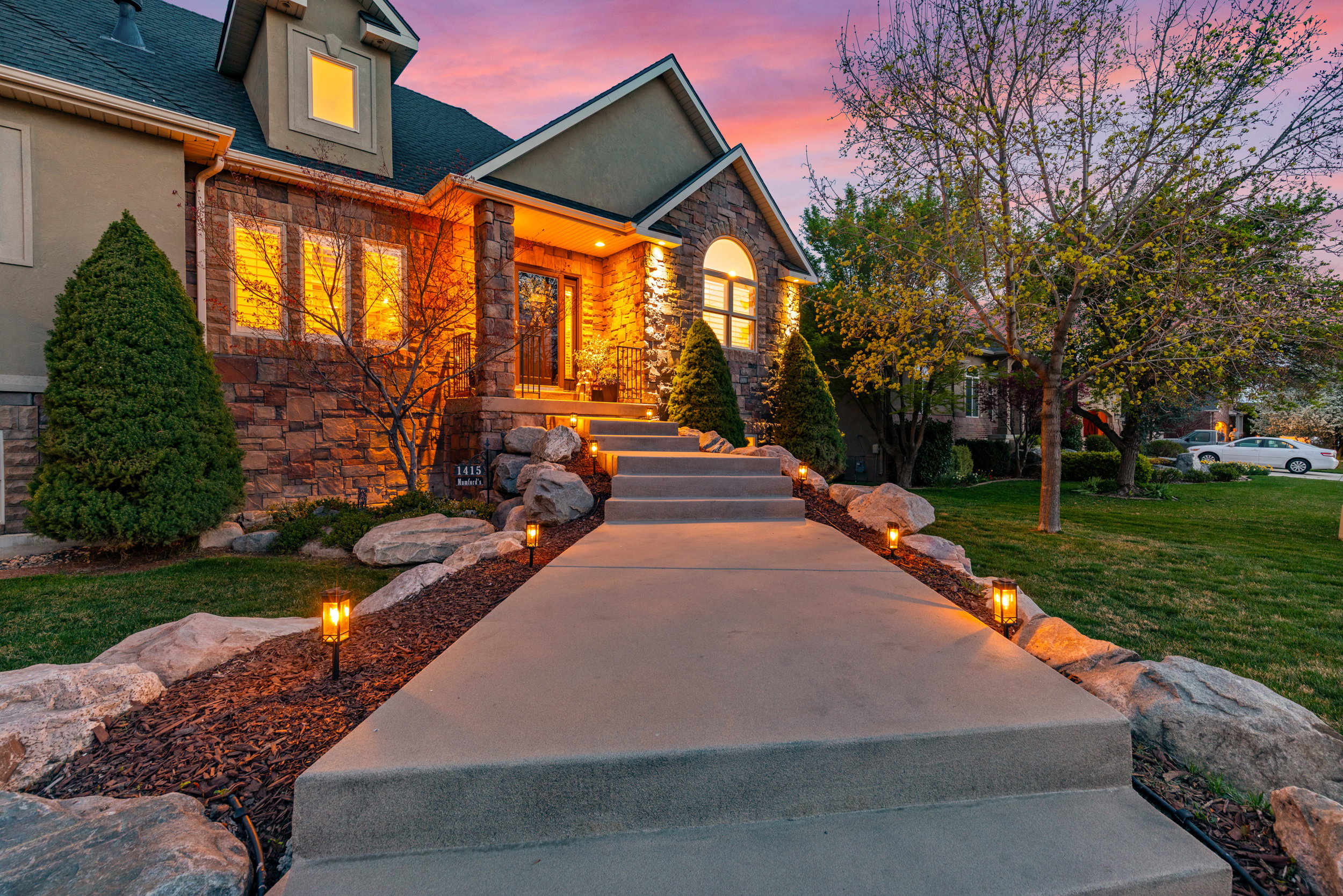 View of front facade featuring stone siding, a lawn, and a shingled roof
