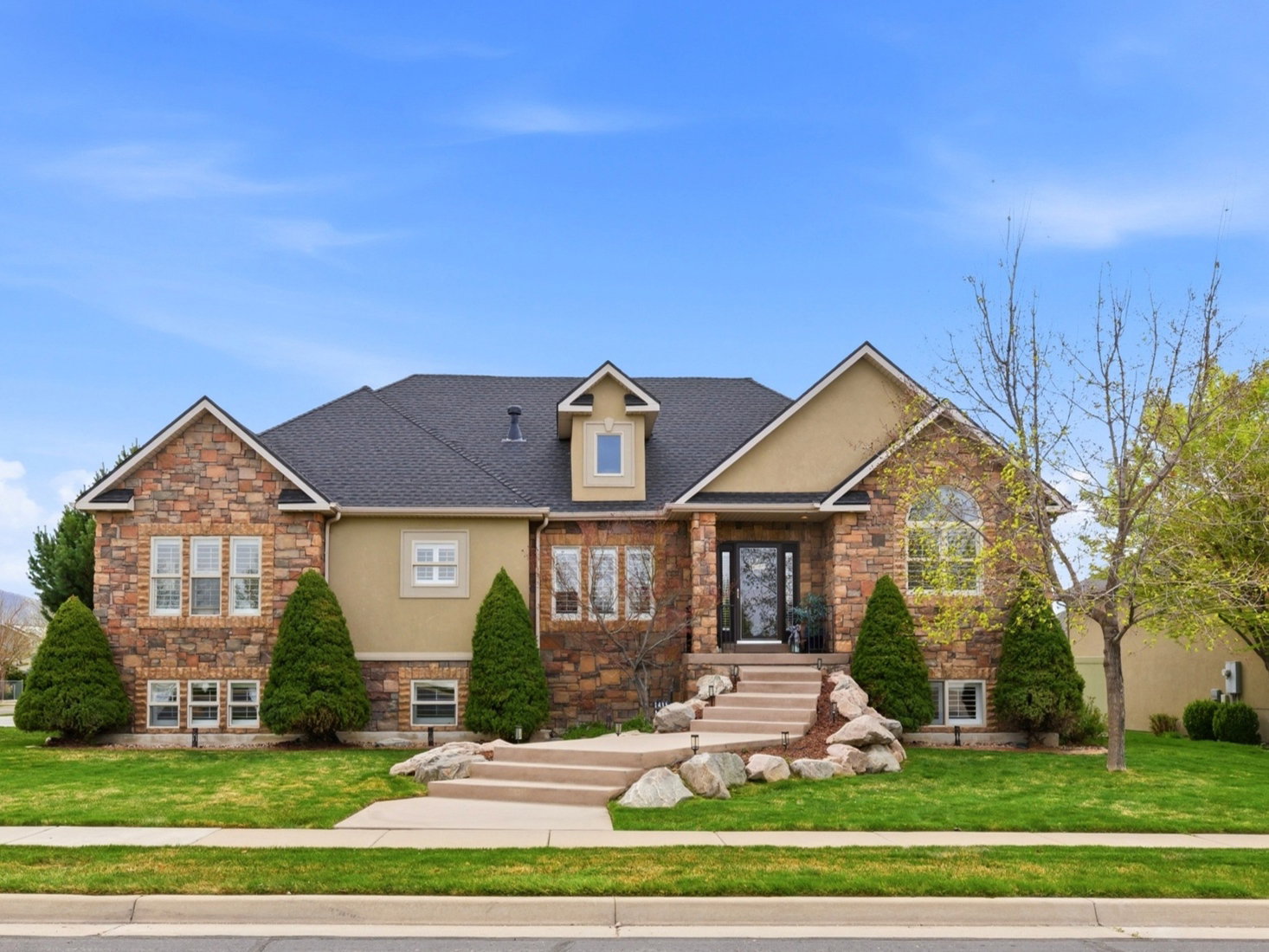 Craftsman-style home featuring a front yard, stone siding, and stucco siding