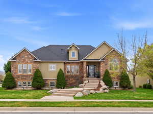 Craftsman-style home featuring a front yard, stone siding, and stucco siding