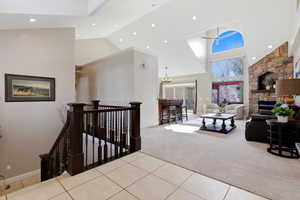 Hall featuring an upstairs landing, light tile patterned flooring, vaulted ceiling, recessed lighting, and light carpet