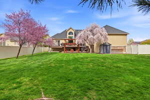 Back of house with a gate, a fenced backyard, a wooden deck, stucco siding, and a shed