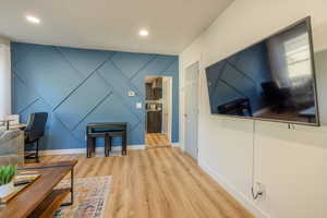 Living room featuring a decorative wall, wood finished floors, an accent wall, and recessed lighting