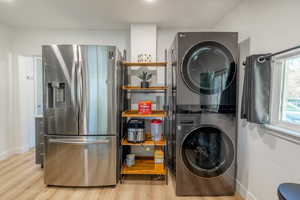 Laundry area with light wood-type flooring and stacked washer / drying machine