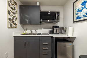 Kitchen featuring light countertops, stainless steel fridge, black electric cooktop, and gray cabinetry