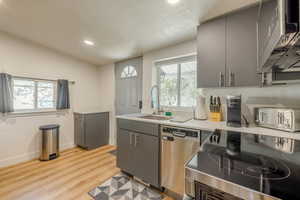 Kitchen featuring stainless steel appliances, gray cabinets, recessed lighting, light countertops, and light wood-type flooring