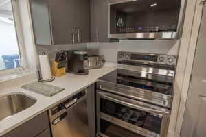 Kitchen with stainless steel appliances and light stone counters