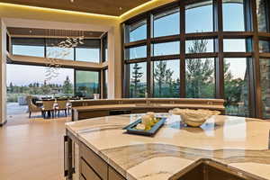 Kitchen with light stone countertops, a mountain view, suspended lighting, light wood-style floors, and a high wooden ceiling