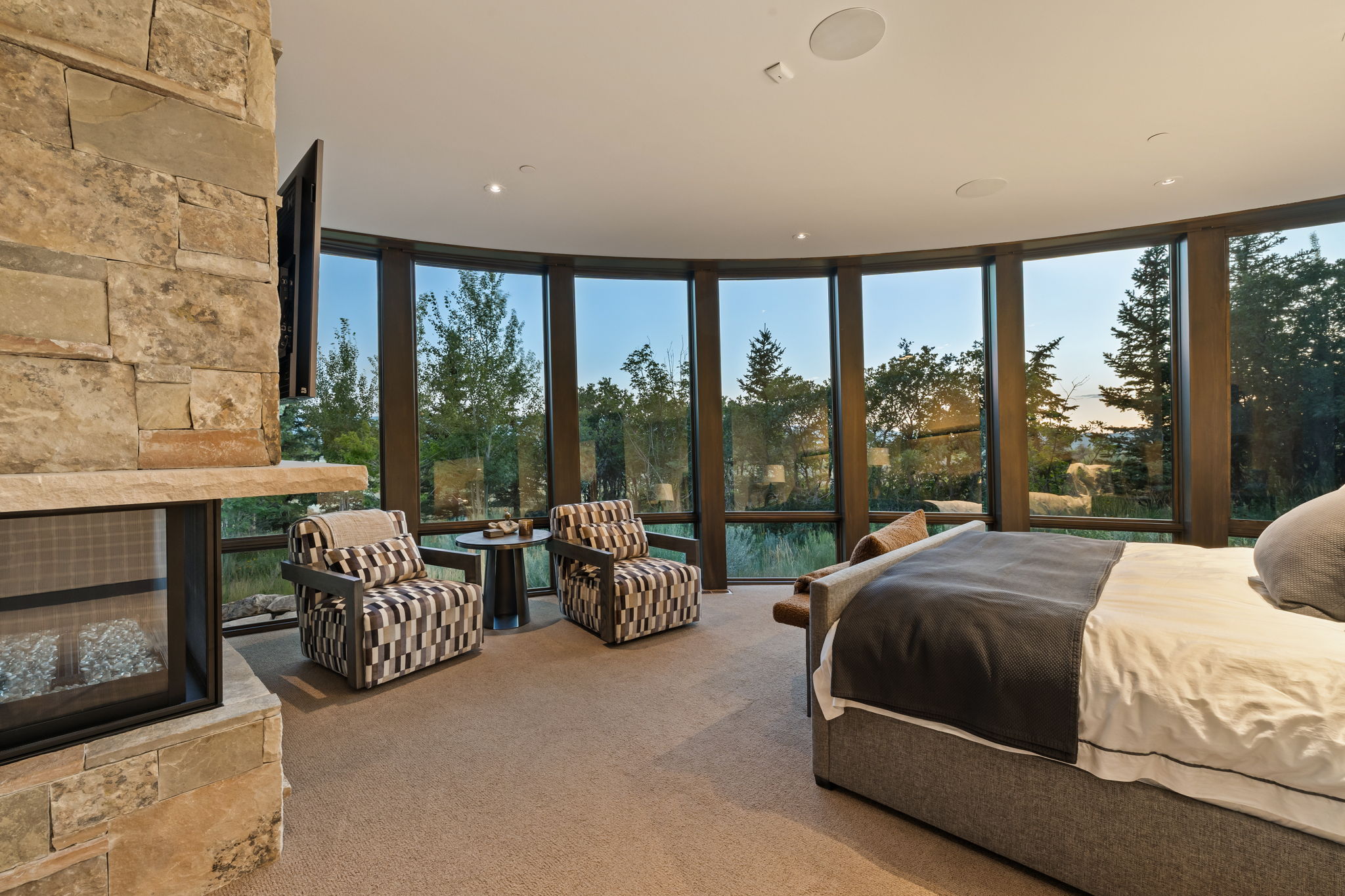 Bedroom with floor to ceiling windows, a stone fireplace, multiple windows, and carpet floors