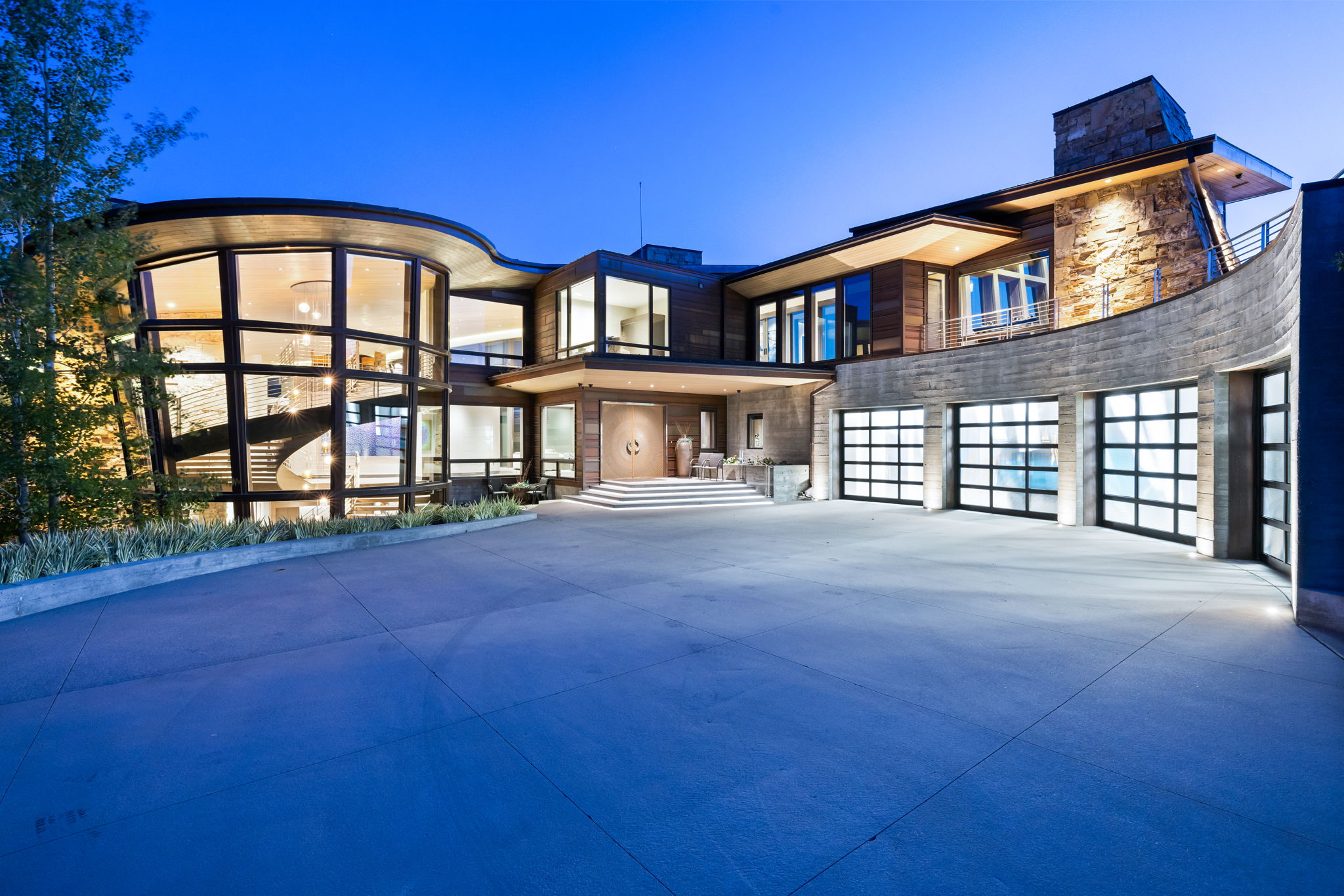 Contemporary home with stone siding, driveway, a garage, and a balcony