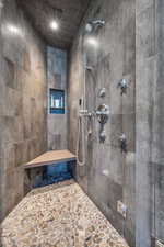 Full bath with tiled shower, stone flooring, and recessed lighting