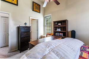 Bedroom featuring carpet floors, ceiling fan, and a high ceiling