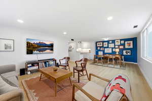 Large open living/dining space area with light engineered wood  floors and recessed lighting