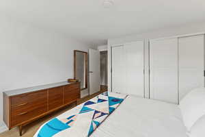Bedroom with multiple closets and wood finished floors