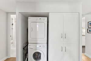 Laundry room with light wood-type flooring and stacked washer and clothes dryer