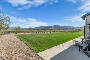 Expansive lawn with a concrete patio, gravel pathway, and a perimeter fence