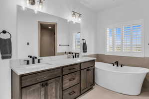 Bathroom featuring a dual-sink vanity with a white countertop, dark wood-finish cabinetry, and matte black fixtures