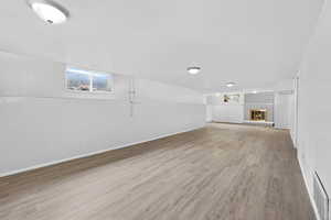 Basement with light wood finished floors and a brick fireplace