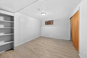 Unfurnished bedroom with wood walls, light wood-style floors, and a closet