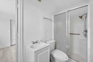 Bathroom with vanity, a stall shower, and light wood-style floors