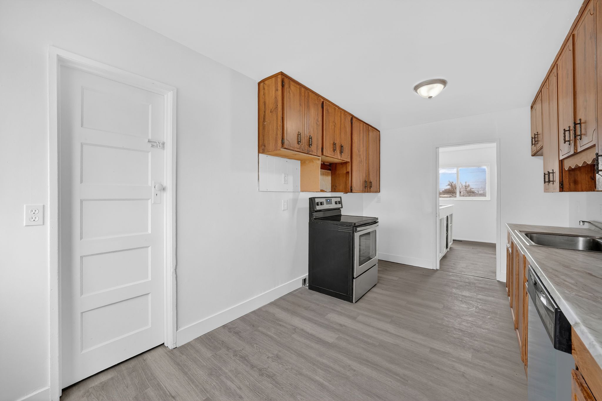 Kitchen featuring wood finish cabinetry, stainless steel appliances, light wood-style floors, and light countertops