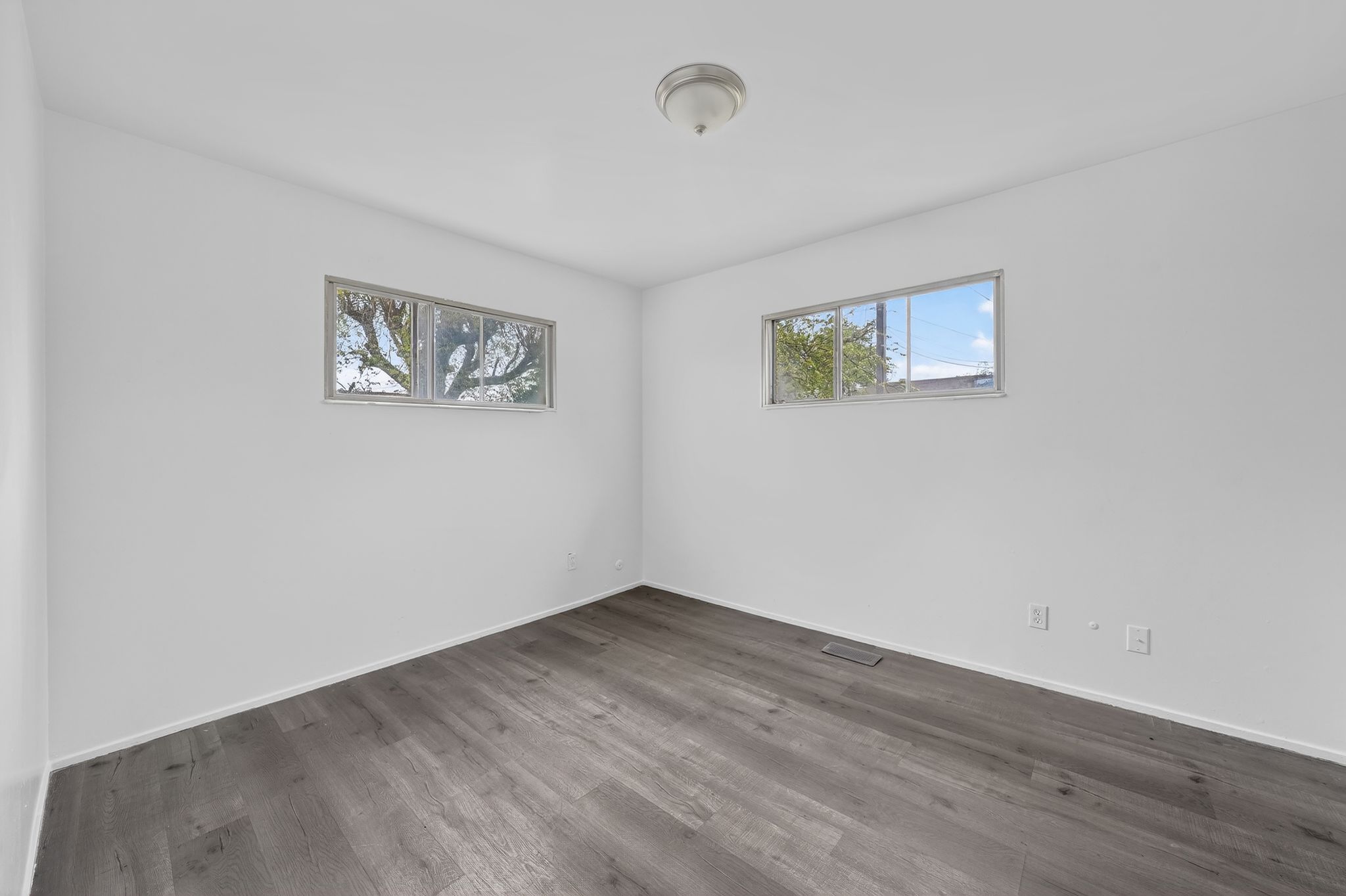 Spare room featuring dark wood-style flooring and baseboards