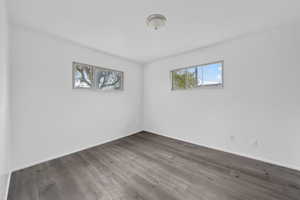 Spare room featuring dark wood-style flooring and baseboards
