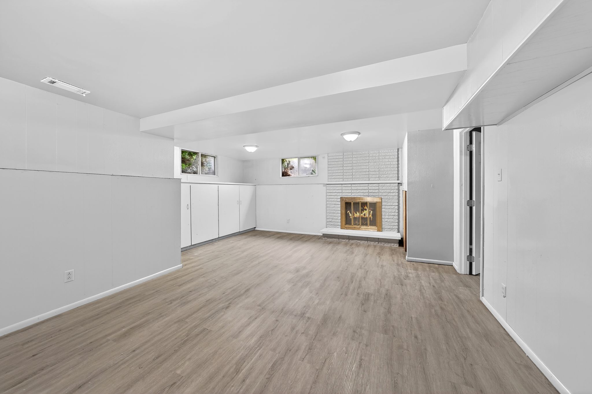 Basement with a brick fireplace and light wood-style floors