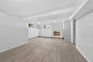Basement with a brick fireplace and light wood-style floors