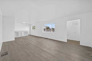 Unfurnished living room featuring dark wood-type flooring and baseboards