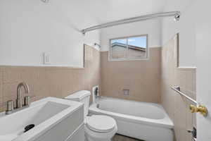Bathroom with tile walls, vanity,  shower combination, and wainscoting