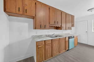 Kitchen featuring light countertops, light wood-type flooring, wood finish cabinets, and dishwasher