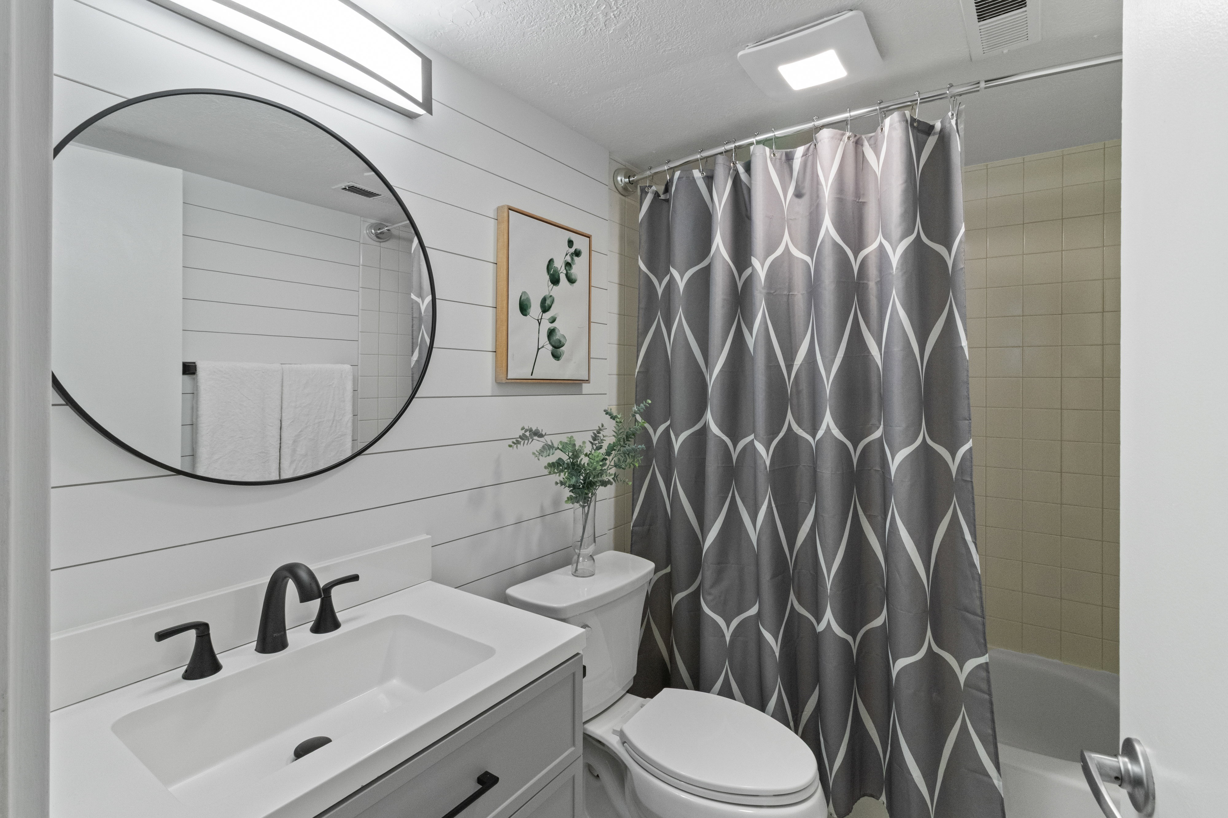 Full bath with vanity, wooden walls, shower / tub combo, and a textured ceiling